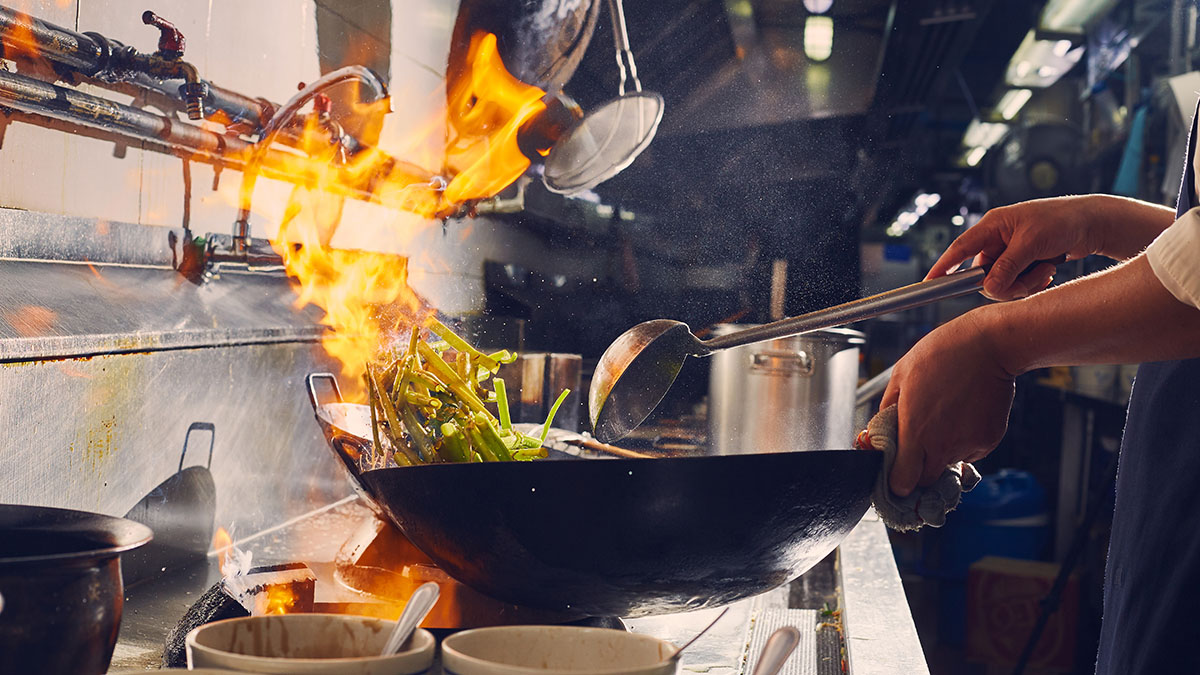 A wok in a kitchen with flames showing Shifu brand photo style