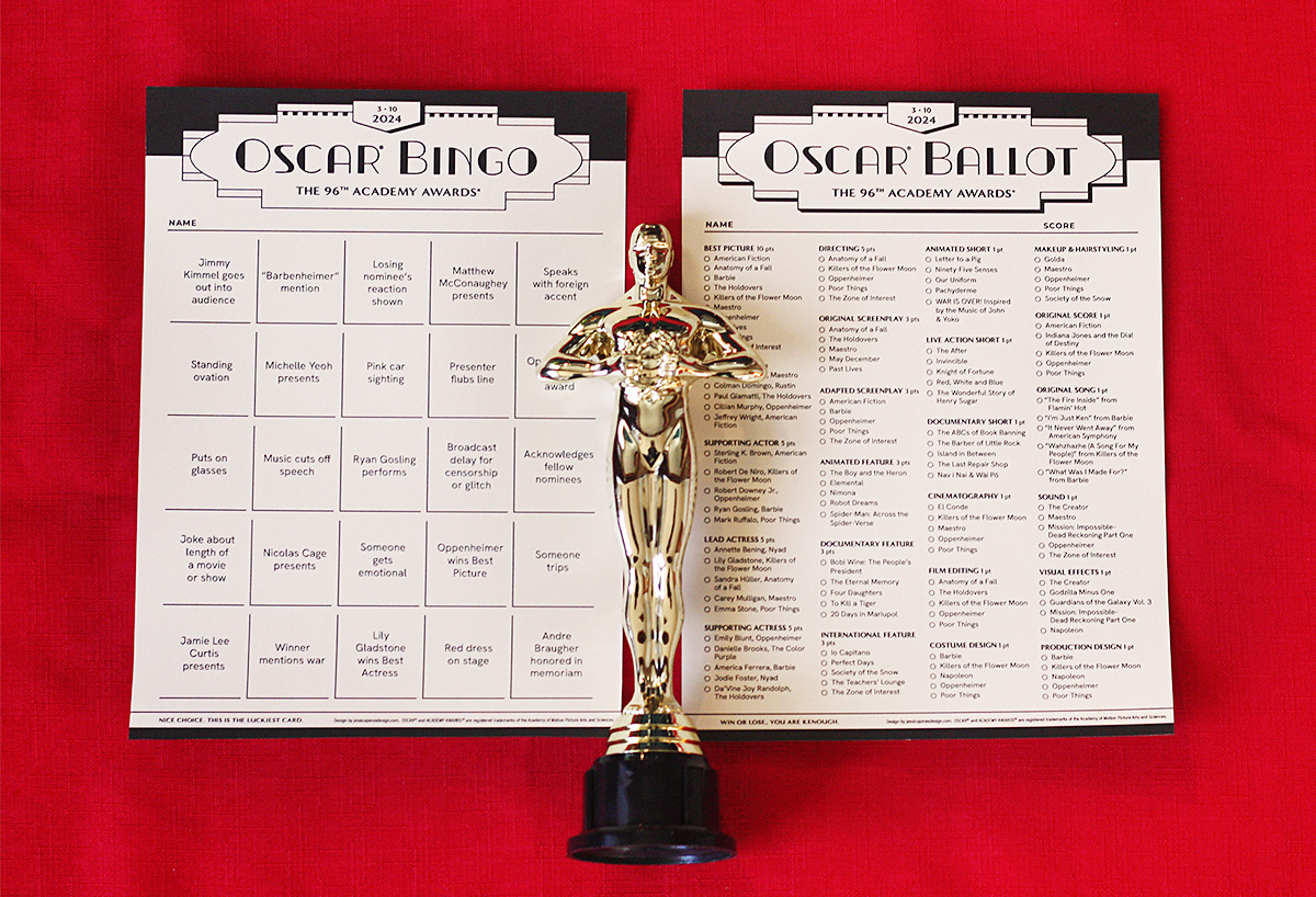 Oscar bingo sheet and ballot page placed on red background with gold Oscar statute lying on top 