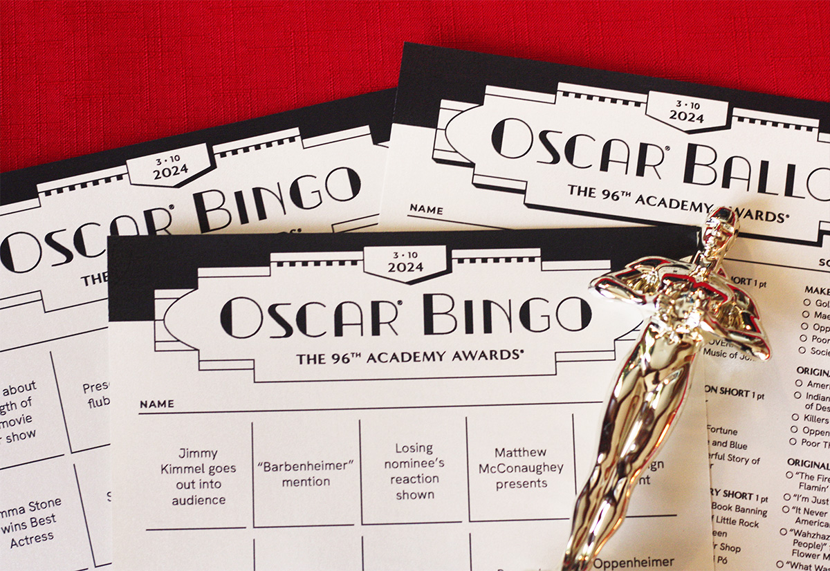 Printed 2024 Oscar bingo card and ballot sheet on red background with Oscar statue lying on top