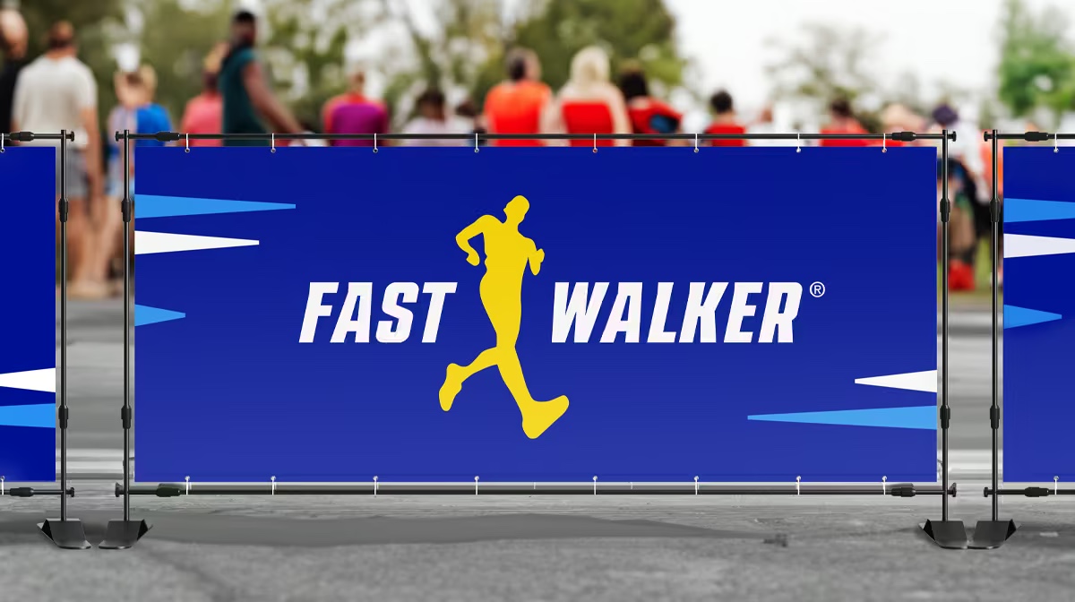 A blue vinyl banner with a FastWalker logo hung on a race barricade